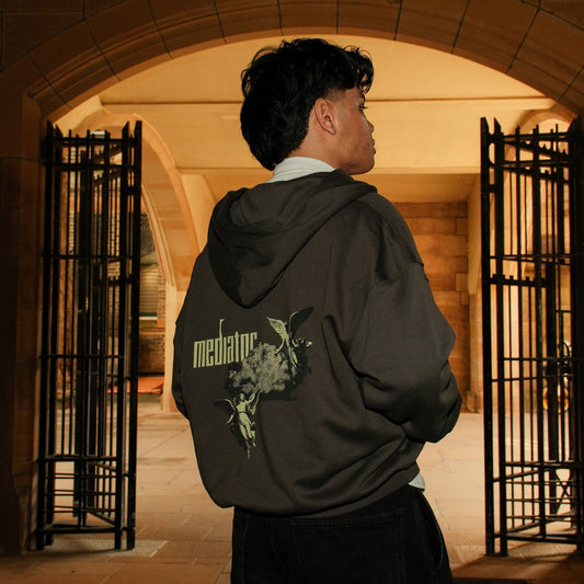 Person wearing a hoodie with a mediator logo in an archway setting