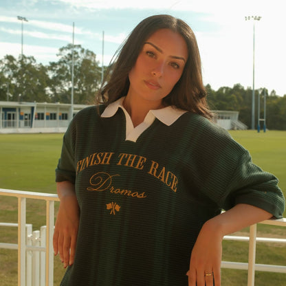 Woman wearing a green christian knit polo shirt with text finish the race on a sports field