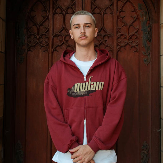 Person wearing a red hoodie with 'owlam' logo in front of a decorative wooden door.