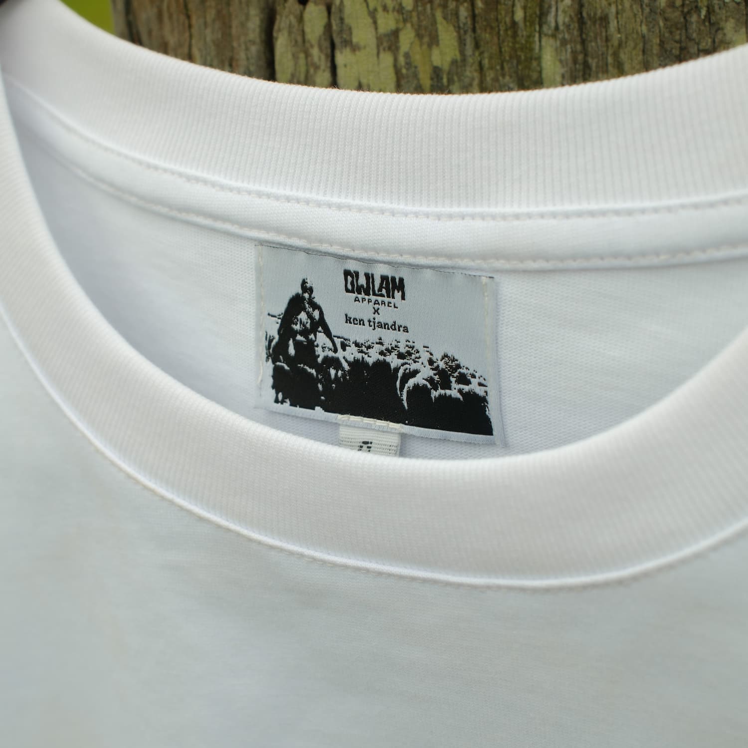 Close-up of a white shirt with a brand label featuring black graphics and text.