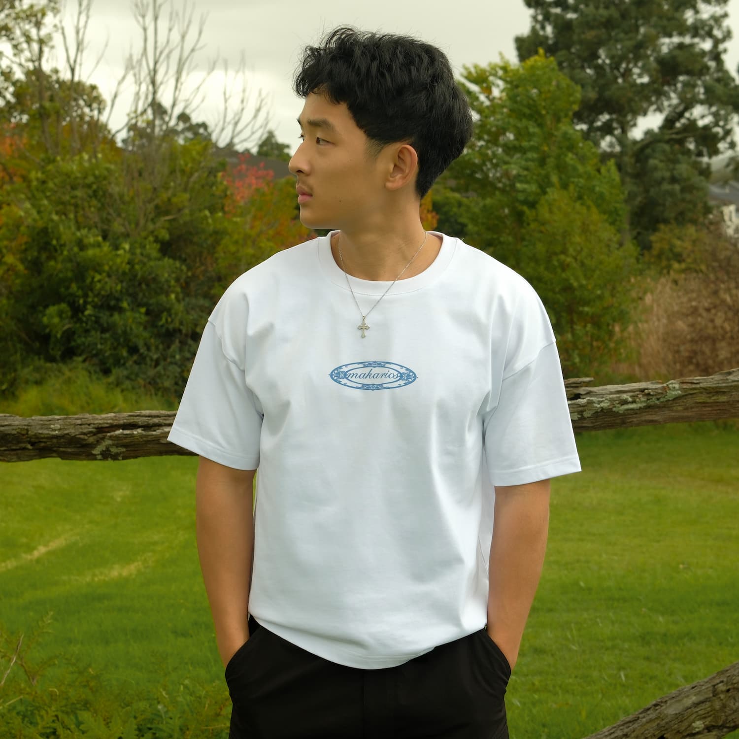 Person wearing a white t-shirt with a logo in an outdoor setting